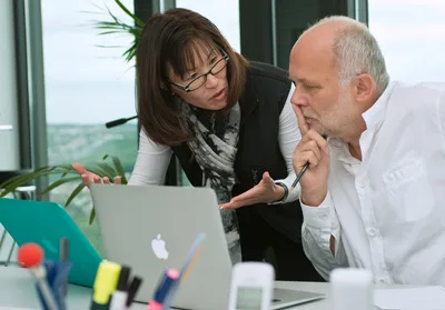 Nancy Chou and a colleague discussing work at a laptop.